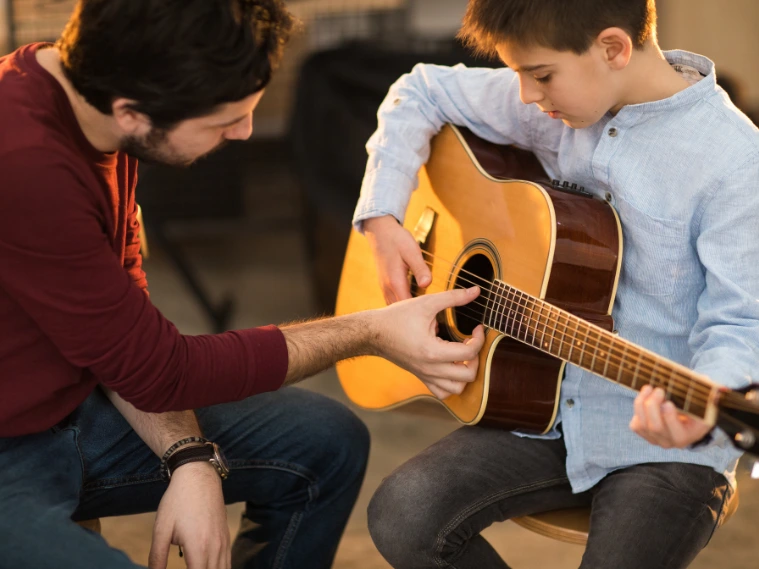Close-up of beginner playing chords on an acoustic guitar