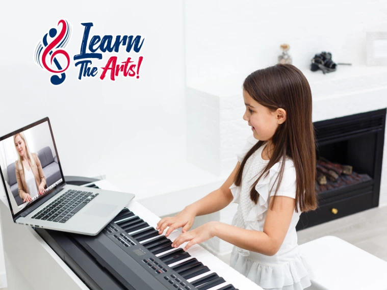 A young child participating in an online music workshop at home, using a laptop and headphones while playing a small instrument in a quiet learning space