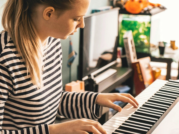 Beginner student practicing simple piano songs on a keyboard at home, following sheet music with proper hand position