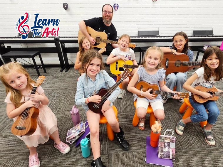 A group of young children playing various musical instruments in a bright, cheerful music classroom at Learn the Arts