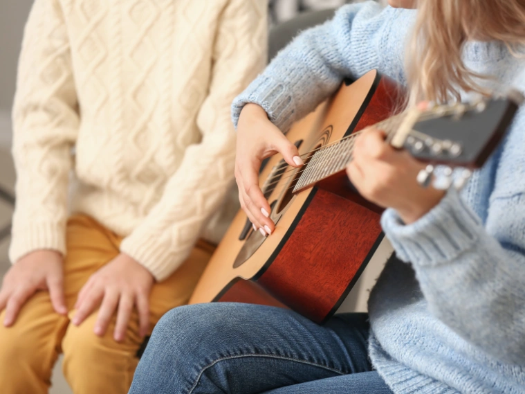 Close-up of a beginner practicing finger exercises on a guitar during a lesson