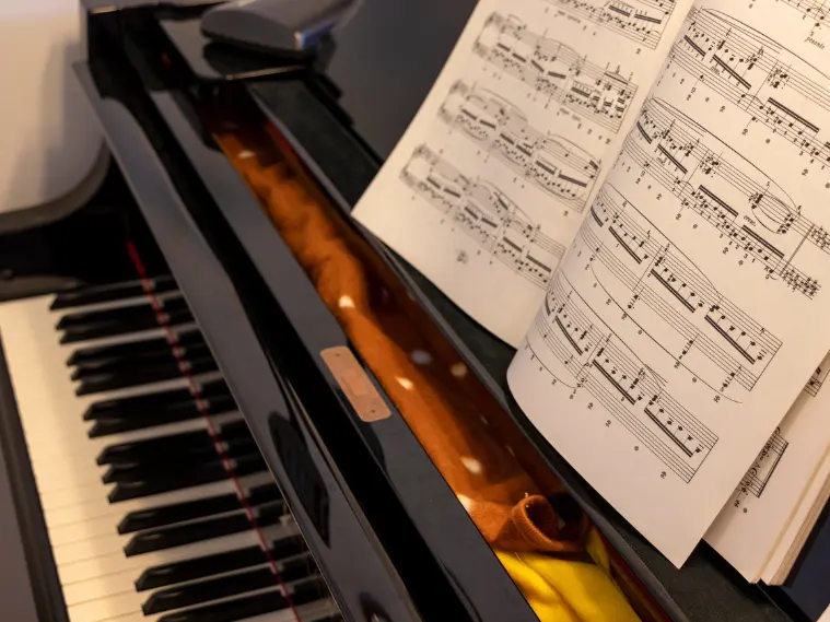 Acoustic piano with sheet music and musical notes, representing piano learning and performance across classical, jazz, and pop styles