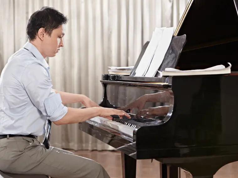 Adult beginner practicing piano at home with sheet music on stand and hands on keyboard