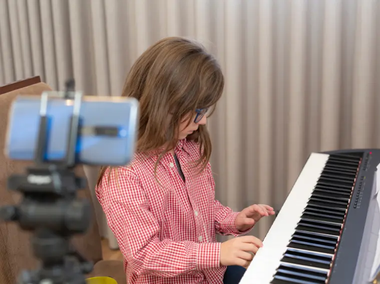 Beginner piano student practicing basic finger exercises on a keyboard during a piano lesson.