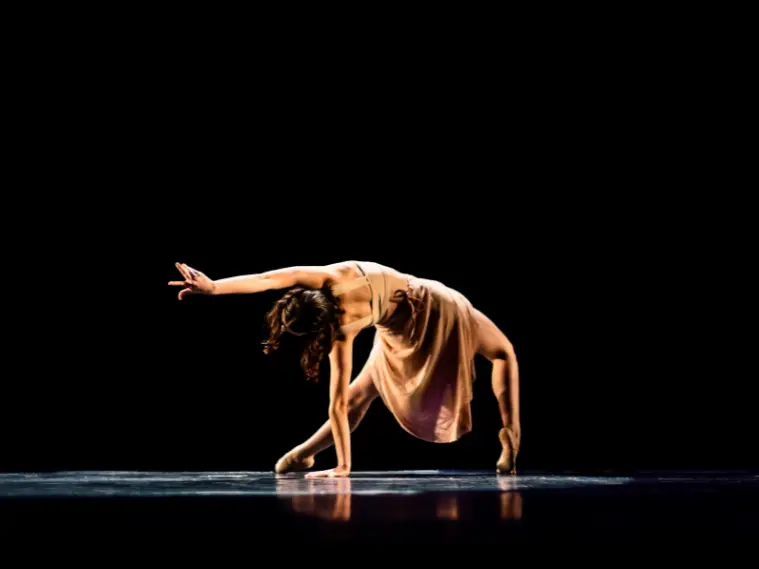 An expressive dancer performing an emotional contemporary routine on stage
