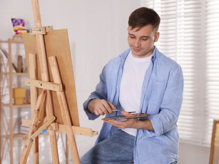 Artist creating a mixed media piece using paint, paper, and textured materials on a workspace