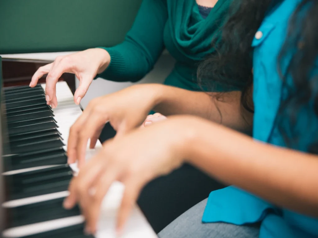 Close-up of hands-on piano keys during a guided lesson with a teacher in California.