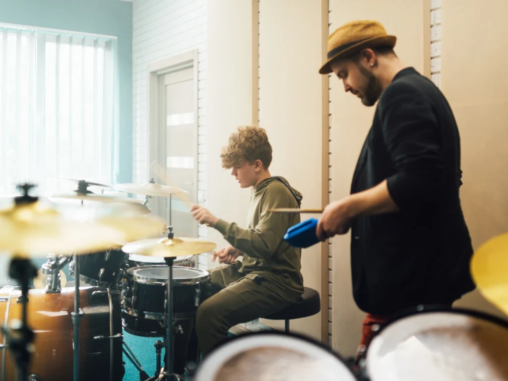 Drum instructor teaching rhythm and coordination skills to a beginner student in a California music studio