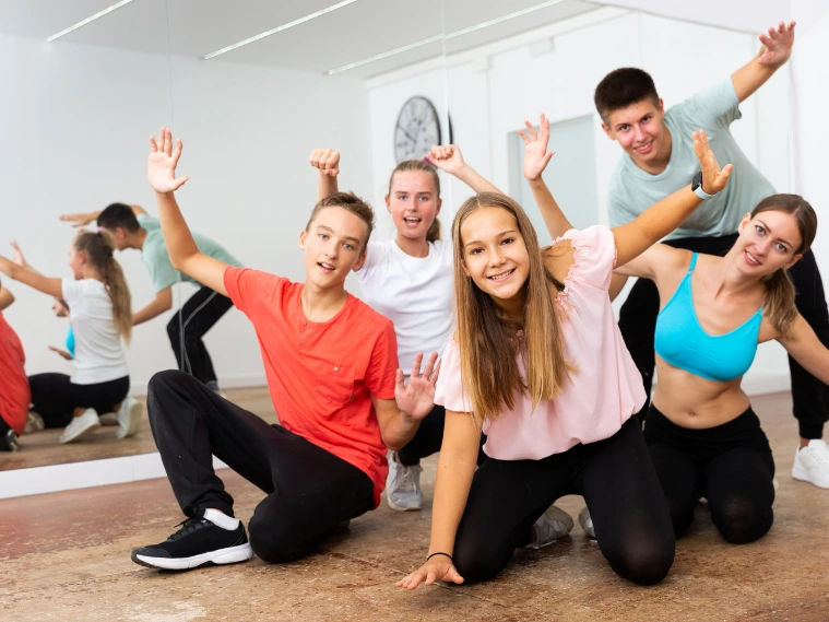Group of dancers practicing different dance styles in a studio with music playing