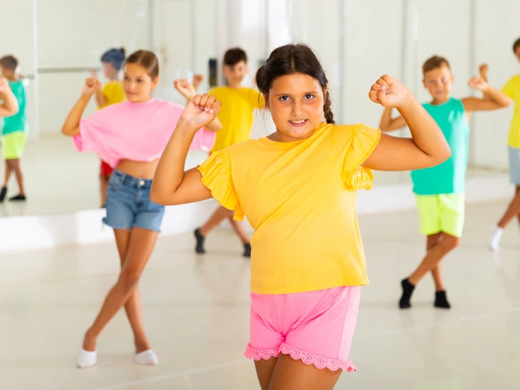 Group of students performing various popular dance styles on stage with colorful costumes and lighting
