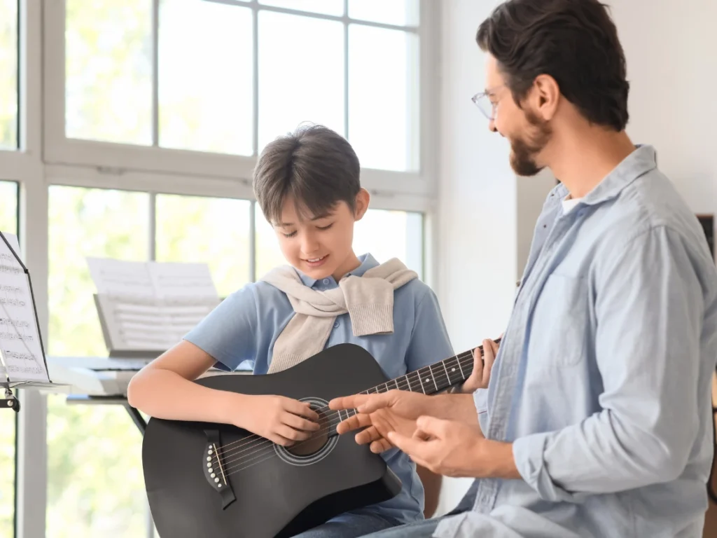 One-on-one guitar lesson in a Westminster, CA music school showing instructor demonstrating chords to beginner student