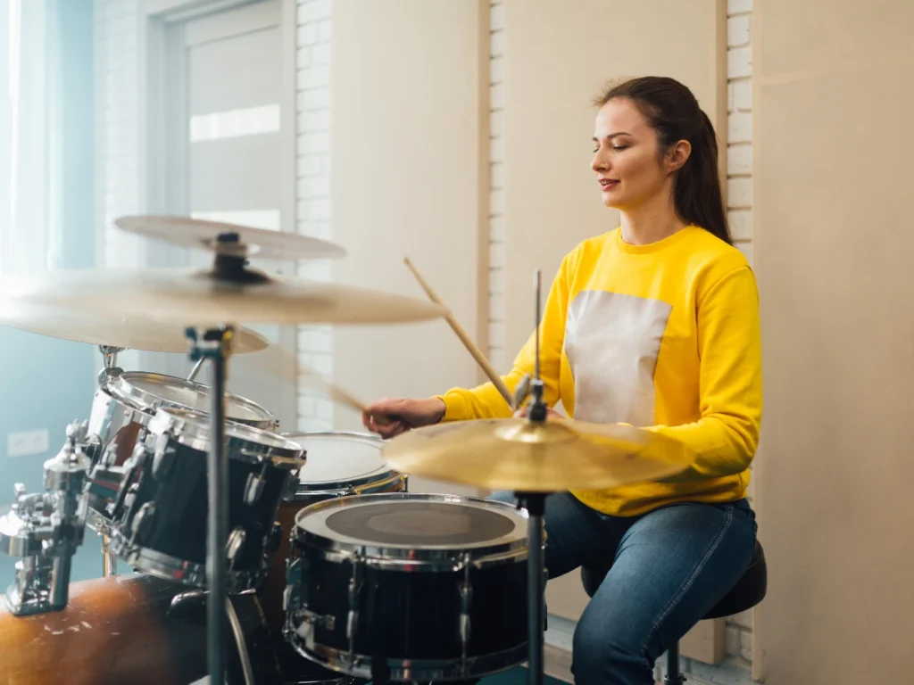 Student practicing basic drum techniques on an acoustic drum set during a beginner drum lesson in California