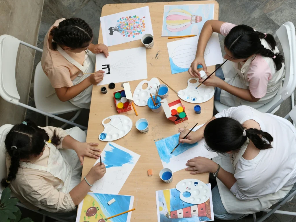 Group of artists painting in a bright California art studio, exploring different painting techniques and expressing creativity through artwork