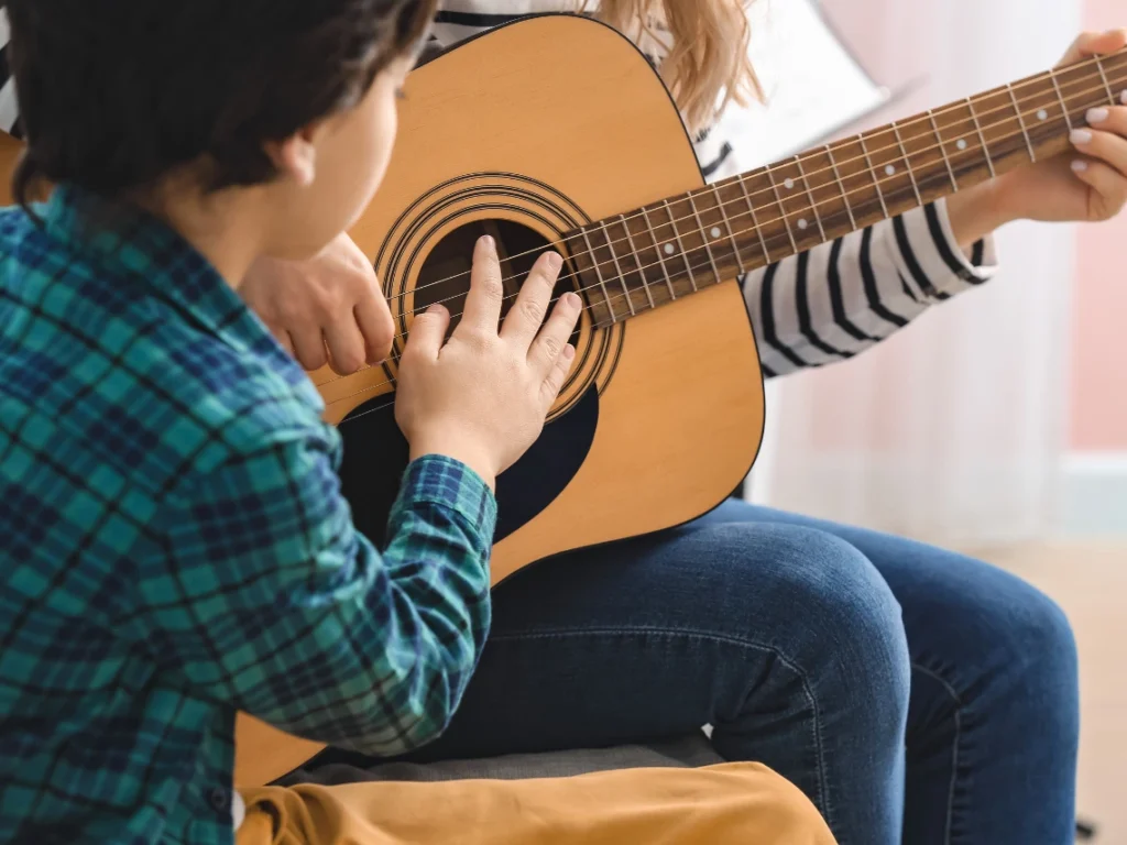 Student practicing acoustic guitar during a private guitar lesson in Las Vegas, NV music school