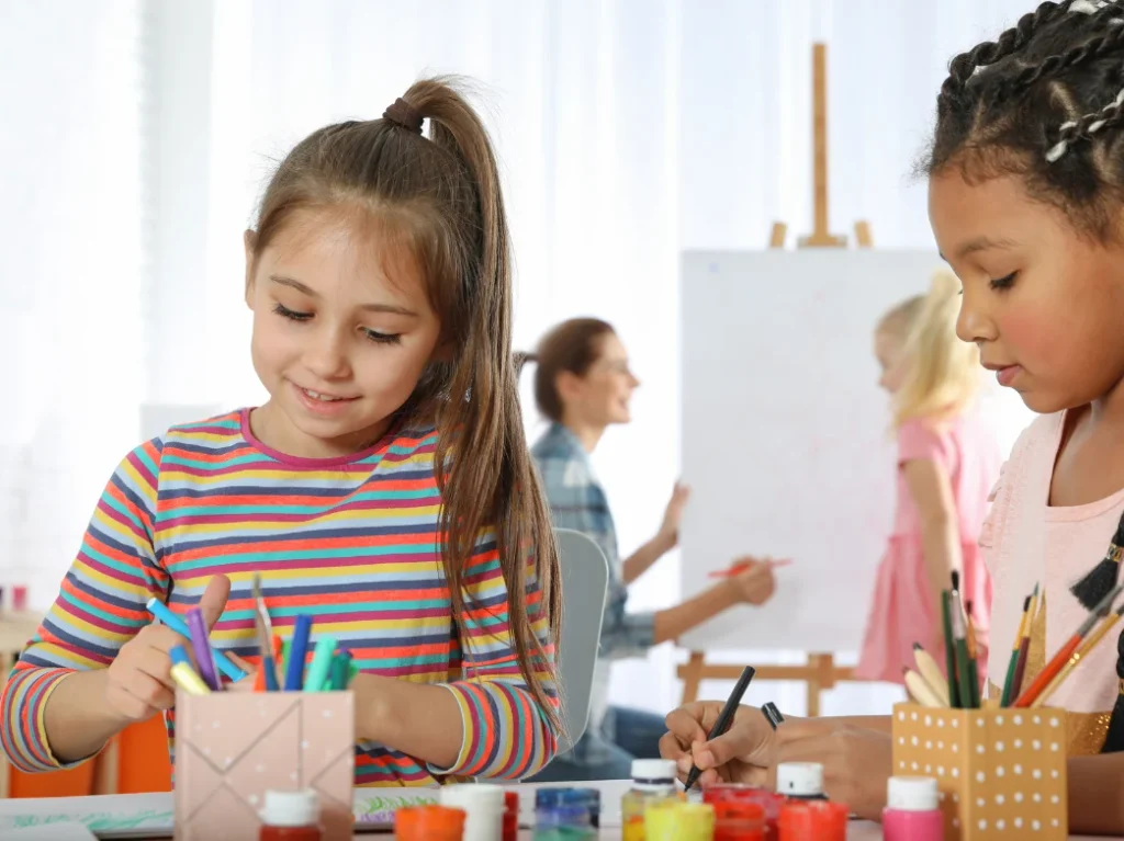 Children creating artwork with colorful paints and art supplies during a beginner painting class.