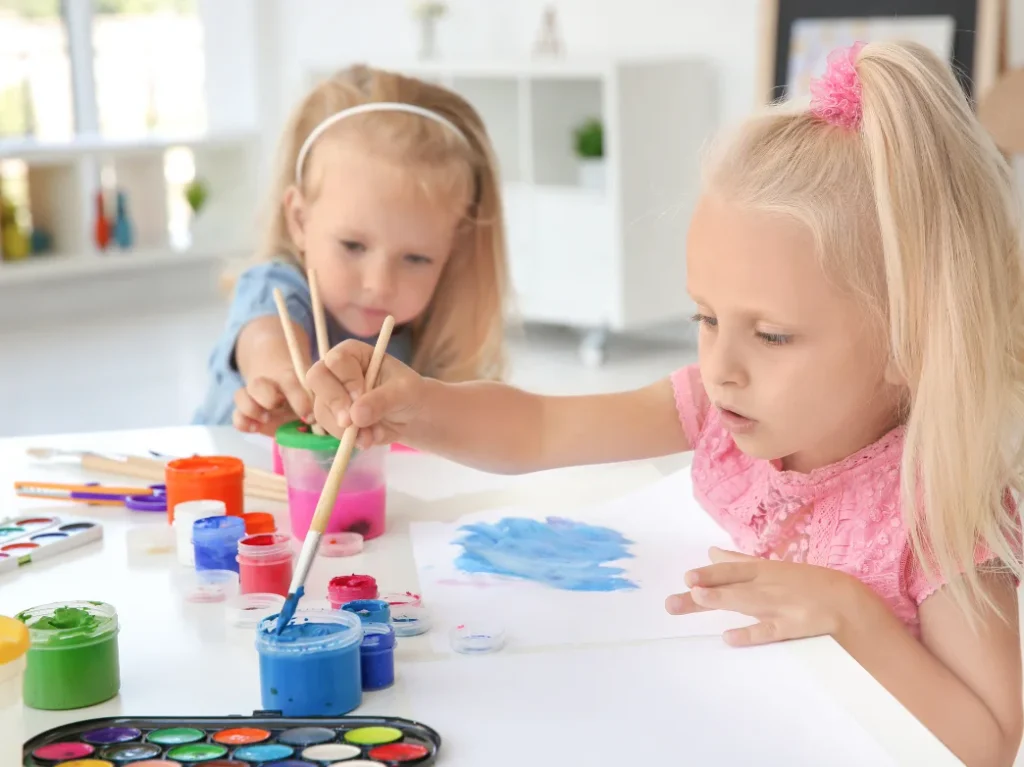 Children exploring colors and creativity while painting with brushes during a beginner art class.