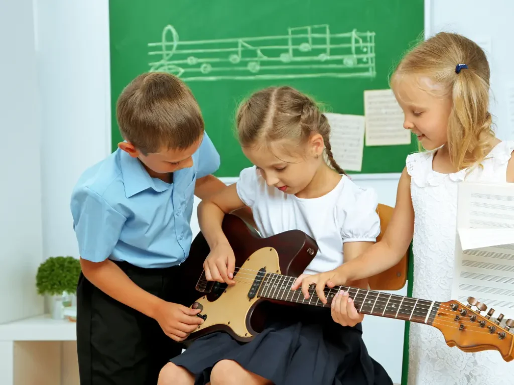 Children learning to play electric guitar together during a group music lesson