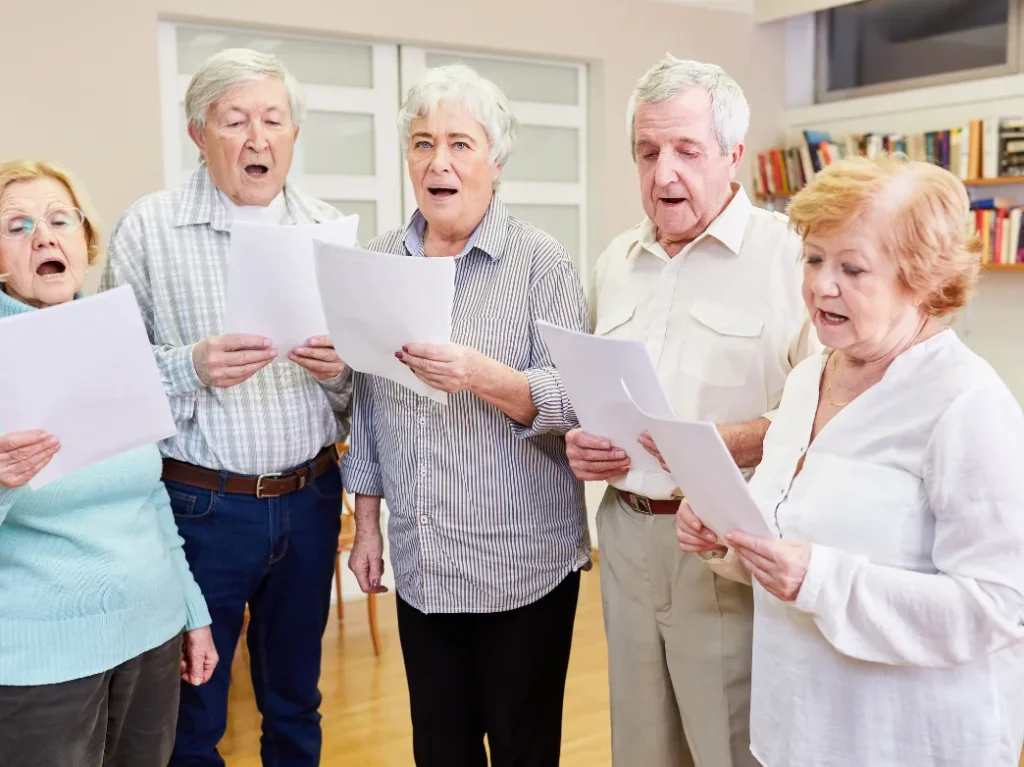 Older adults participating in a group vocal lesson, singing together while following sheet music.