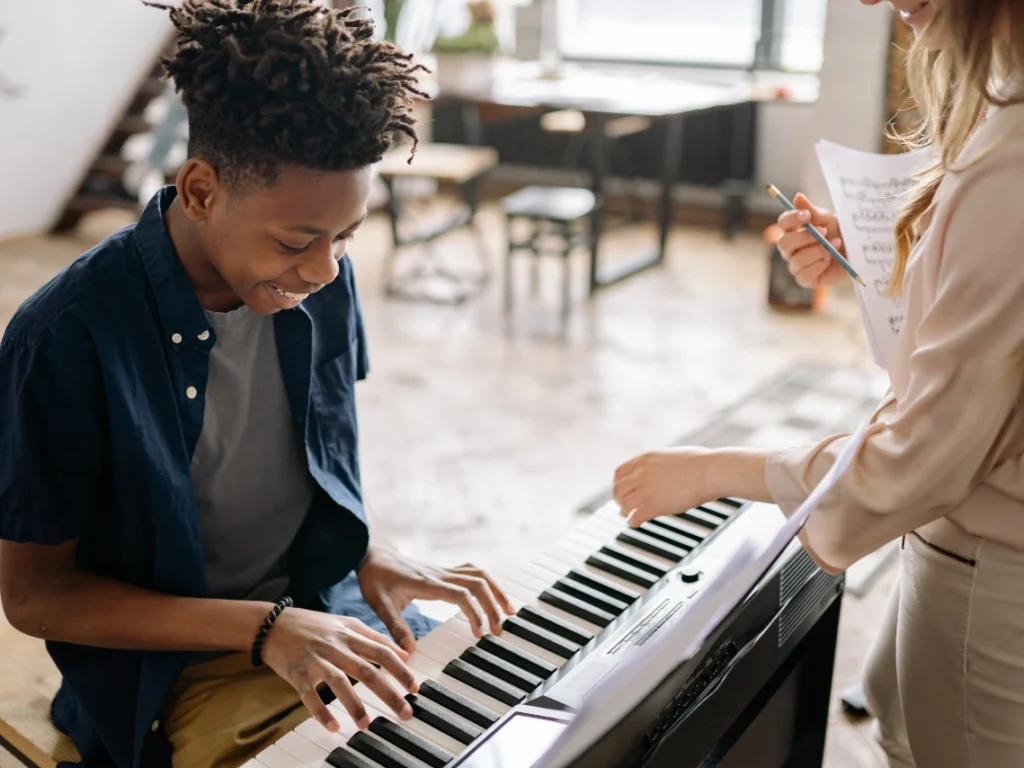 Student learning piano in a professional Gilbert, AZ music studio with an experienced instructor guiding hand placement.