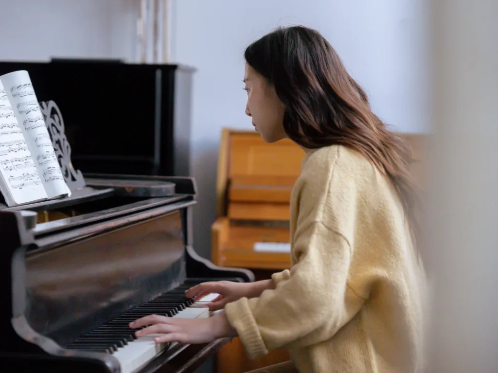 Adult student practicing piano while reading sheet music during a piano lesson.