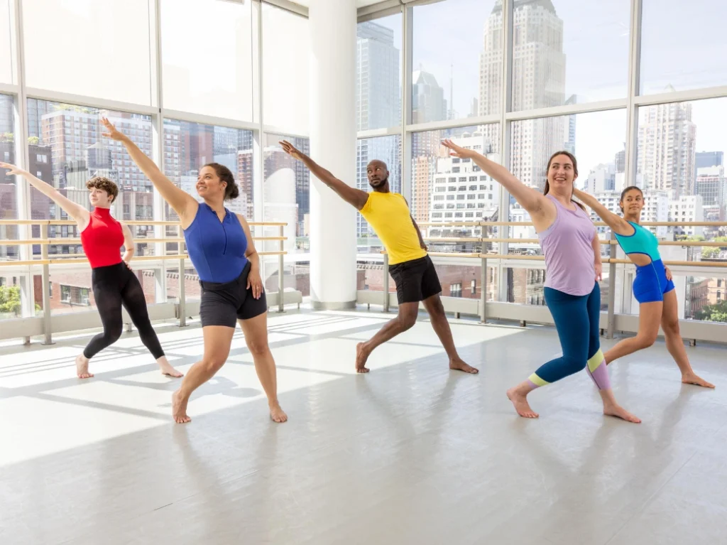 Adults practicing jazz dance choreography together during a group dance class in a bright studio