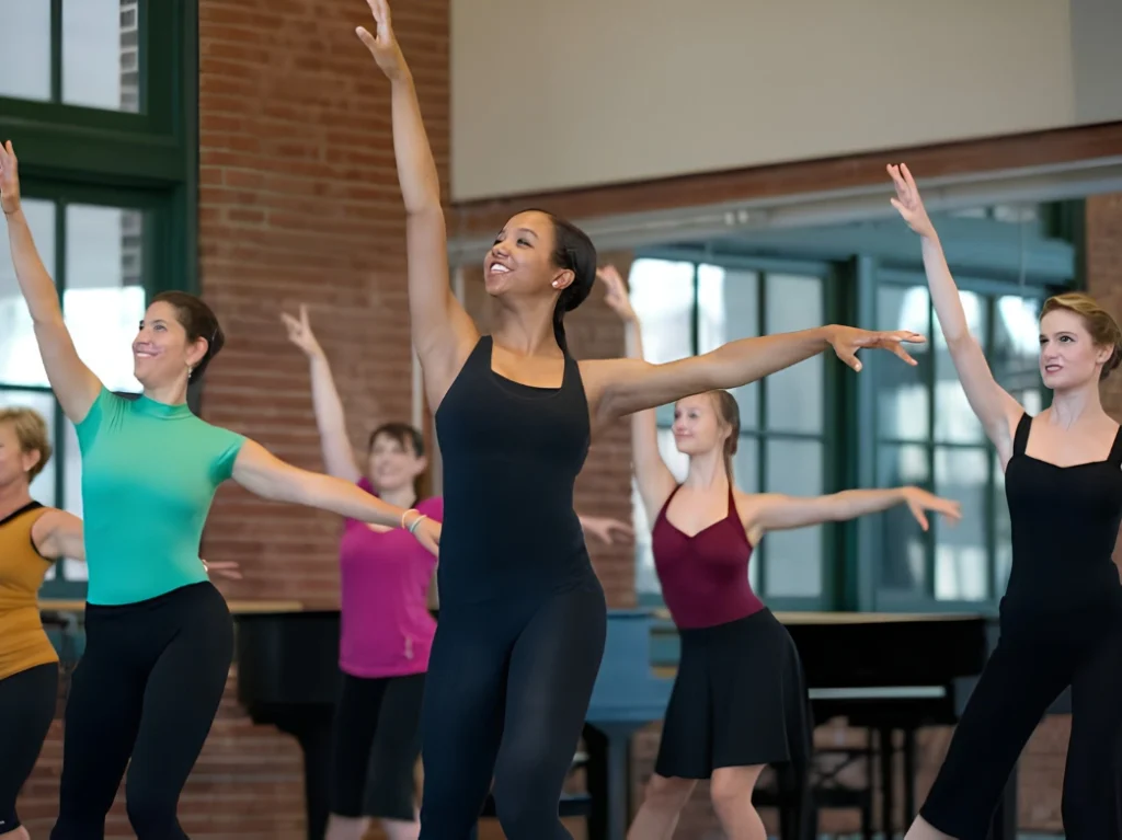Adults practicing jazz dance movements together during a group dance class in a studio