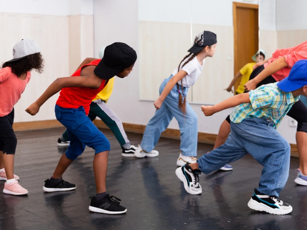 Kids practicing hip-hop dance moves together during a group dance class in a studio.